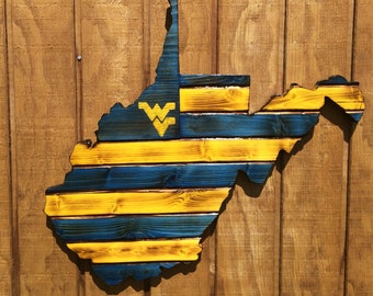 May include: A wooden cutout of the state of West Virginia painted in blue and yellow stripes with the West Virginia University logo in the center.