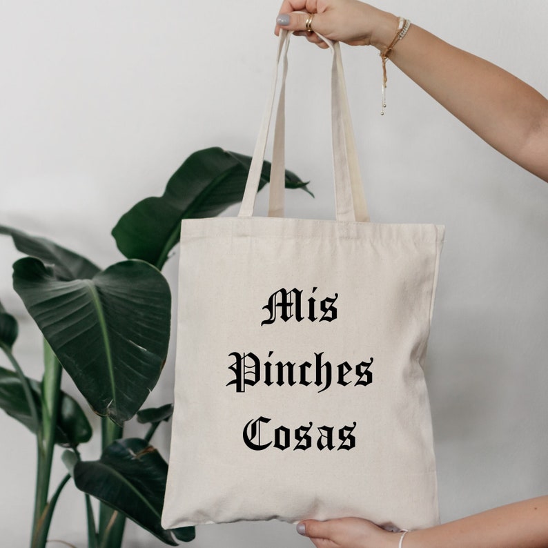 K&ouml;nnte beinhalten: Eine wei&szlig;e Canvas-Tragetasche mit schwarzem Text, der "Mis Pinches Cosas" lautet.