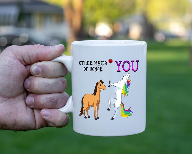 May include: White ceramic mug with a unicorn and a horse illustration. The text on the mug reads "Other maids of honor" and "You" with a pink diamond between the two phrases.