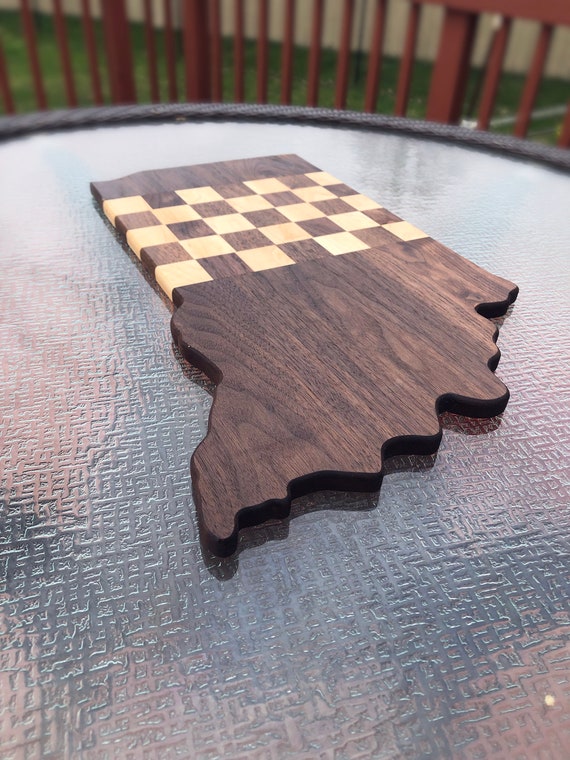 A handcrafted wooden cutting board inlaid with a checkered racing flag pattern — functional charcuterie art for the motorsports fan who actually uses their kitchen.