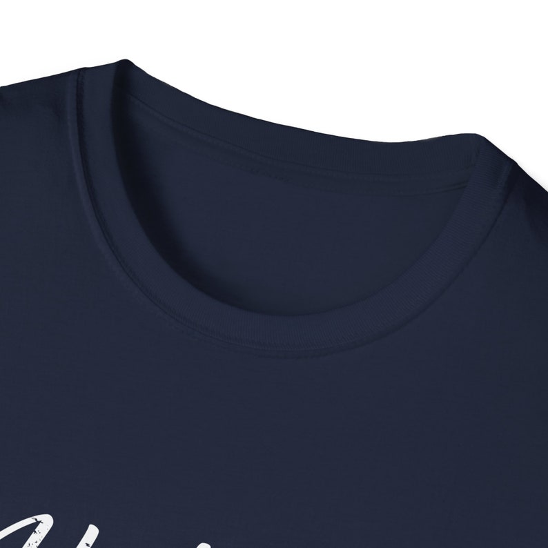 Puede incluir: Una camiseta azul marino con un dise&ntilde;o gr&aacute;fico blanco. El dise&ntilde;o gr&aacute;fico es una palabra en cursiva.