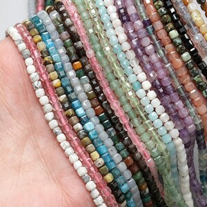 Puede incluir: Primer plano de una selección de cuentas de piedras preciosas en varios colores, incluyendo rosa, verde, azul y morado. Las pequeñas cuentas facetadas están ensartadas, ideales para la creación de joyas. La imagen ofrece una vista detallada de las cuentas.