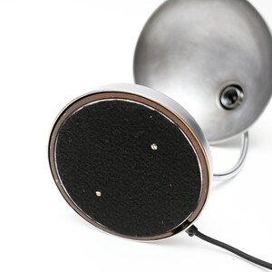 May include: A chrome desk lamp with a round, silver shade and a black felt base. The lamp has a cord and a switch.