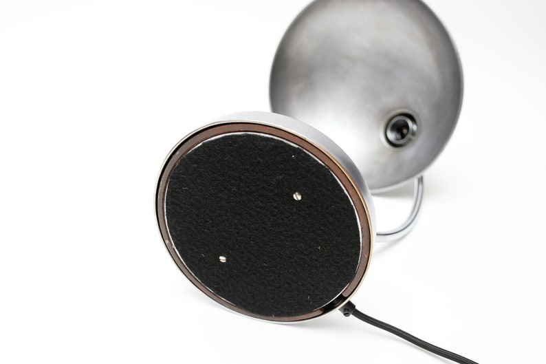 May include: A chrome desk lamp with a round, silver shade and a black felt base. The lamp has a cord and a switch.