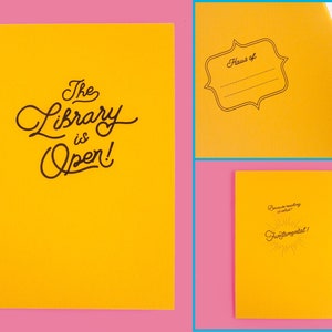 Puede incluir: Un conjunto de tres cuadernos amarillos. El primer cuaderno tiene el texto "The Library is Open!" en escritura negra. El segundo cuaderno tiene una etiqueta que dice "Haus of" con l&iacute;neas para escribir. El tercer cuaderno tiene el texto "Because reading is what? Fundamental!"