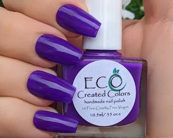 May include: A small bottle of purple nail polish with a white cap. The bottle is labeled "ECO Created Colors handmade nail polish 10 free Cruelty free Vegan 10.5ml/.35 oz e".