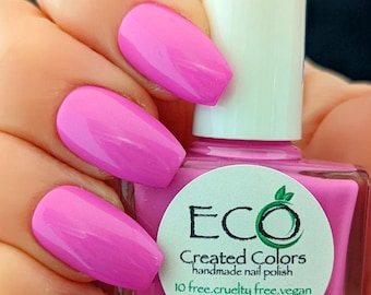 May include: Pink nail polish bottle with a white cap and a green logo that says "Eco Created Colors handmade nail polish 10 free. cruelty free. vegan 10.3ml / .35oz e"