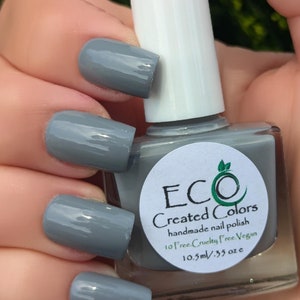 May include: A bottle of gray nail polish with a white label that reads "ECO Created Colors handmade nail polish 10 free. Cruelty Free Vegan 10.5ml/.35 oz e"