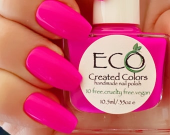 May include: A bottle of bright pink nail polish with a white label that reads "ECO Created Colors handmade nail polish 10 free. cruelty free. vegan 10.5ml / .35oz e"
