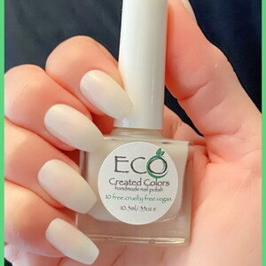 May include: A white bottle of nail polish with a white label that says "ECO Created Colors handmade nail polish 10 free. cruelty free. vegan. 10.5ml/.35oz e"