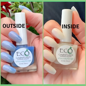 May include: Two bottles of nail polish, one light blue and one white, with the label "ECO Created Colors handmade nail polish 10 free cruelty free vegan 10.5ml/35oz e" on each bottle.