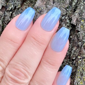 May include: A set of five light blue ombre coffin-shaped press-on nails.