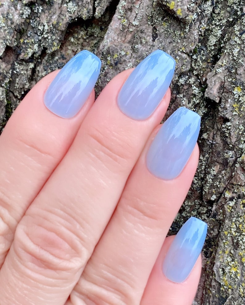 May include: A set of five light blue ombre coffin-shaped press-on nails.