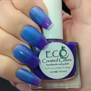 May include: A bottle of blue and purple nail polish with a white label that reads "ECO Created Colors handmade nail polish 10 Free. Cruelty Free. Vegan 10.5ml/.35 oz e".