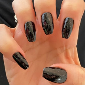 May include: Black glitter nail polish on long, coffin-shaped nails.