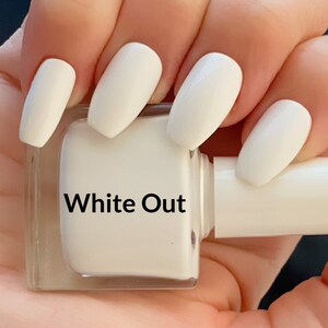 May include: White nail polish bottle with the label "White Out" and a hand with white nail polish on all fingers.