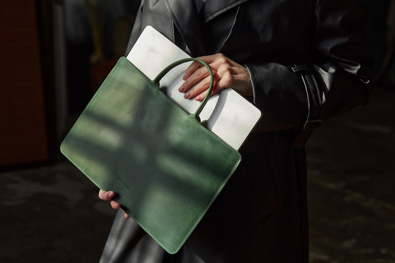 a person holding a green and white bag