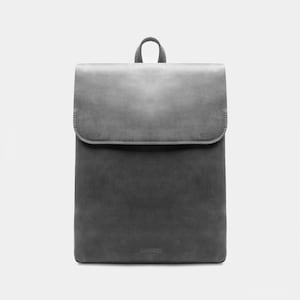 May include: A gray leather backpack with a flap closure and a top handle. The backpack has a minimalist design and a rectangular shape. The brand name "ancorne" is visible at the bottom of the bag.