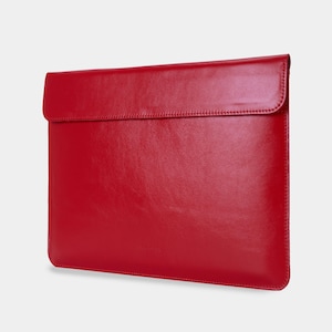 May include: A vibrant red leather laptop sleeve with a flap closure. The sleeve is rectangular with rounded corners and a smooth, polished surface. The design is minimalist and sleek, suitable for protecting a laptop.