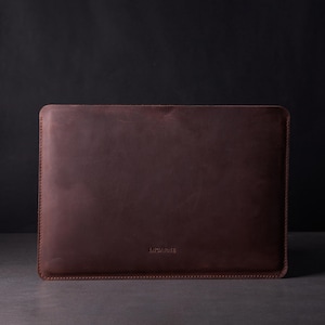 May include: A brown leather laptop sleeve with the word "INCABRIE" embossed on the front.