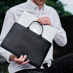 a man sitting on a bench holding a laptop