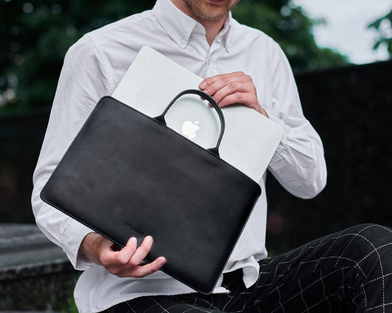 a man sitting on a bench holding a laptop