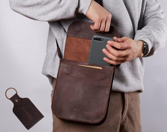 May include: A dark brown leather crossbody bag with a flap closure and a matching leather keychain featuring the embossed text INCARNE. The bag has a rectangular shape with visible stitching and a smooth matte finish on the exterior surface.