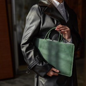 a man in a trench coat holding a green bag