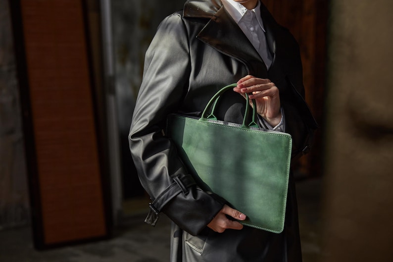 a man in a trench coat holding a green bag