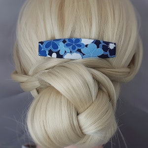 May include: A blue and white floral patterned hair clip. The clip is made of fabric and has a rectangular shape.