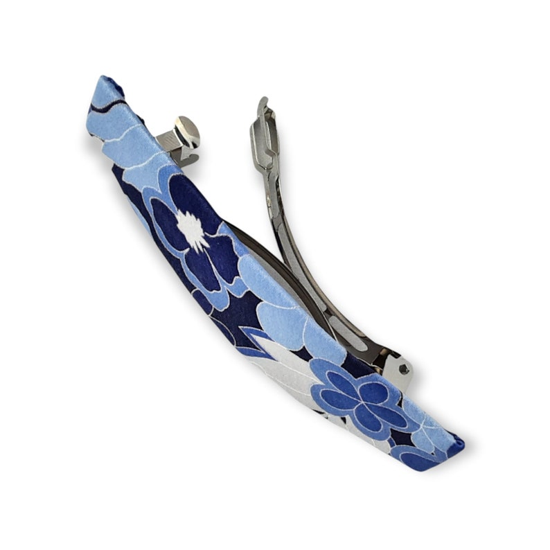 May include: A blue and white floral patterned hair clip with a silver metal clasp.