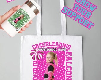 May include: White tote bag and tumbler featuring a cheerleading design. The bag displays a cheerleader image with text: "CHEERLEADING, FALCONS, 2023, CHEER, Team captain." The tumbler is held by a hand and has a similar design. Text: "6 COLOR BUNDLE, SHOW YOUR SUPPORT."