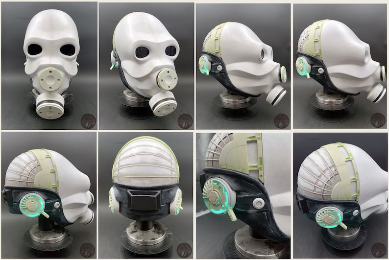 May include: A white helmet with a black strap and green accents. The helmet has a gas mask attached to it. The helmet is on a stand.
