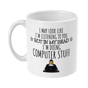Può includere: Una tazza in ceramica bianca con una grafica nera di una persona che indossa una maschera di Guy Fawkes e siede davanti a un computer. Il testo sulla tazza recita "I may look like I'm listening to you but in my head I'm doing computer stuff."