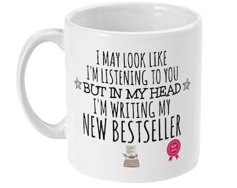 May include: White ceramic mug with black text that reads "I may look like I'm listening to you but in my head I'm writing my new bestseller". There is a small illustration of a typewriter and a red ribbon with the text "Best Seller" on the mug.