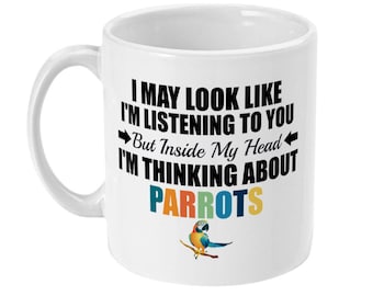 May include: White ceramic mug with a black and white graphic that reads "I may look like I'm listening to you, but inside my head I'm thinking about parrots". A colorful parrot is pictured on a branch below the text.