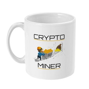 May include: White ceramic mug with a black and gold design. The mug features a cartoon illustration of a miner pushing a cart full of gold coins. The text "CRYPTO MINER" is printed on the mug.