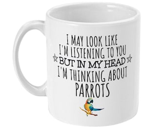 May include: White ceramic mug with a black and white graphic that says "I may look like I'm listening to you but in my head I'm thinking about parrots". A colorful parrot is pictured below the text.