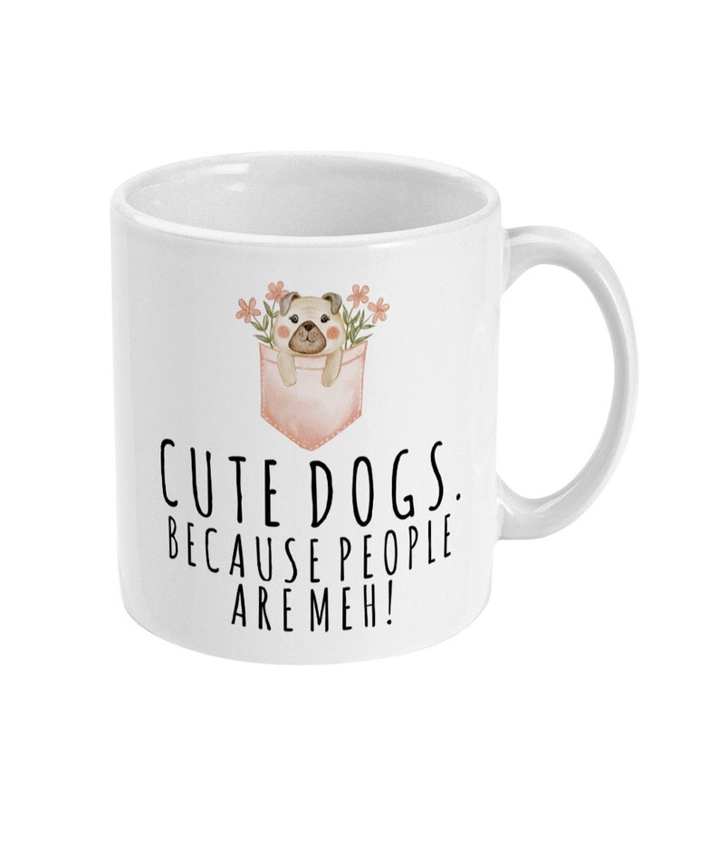 May include: White ceramic mug with a cartoon pug in a pink pocket with flowers. The mug has the text "Cute dogs. Because people are meh!"