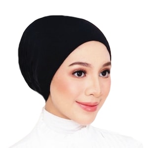 May include: A black stretchy fabric head covering, also known as a hijab, worn by a person with a white shirt.