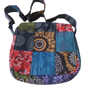 May include: A colourful patchwork shoulder bag with a black strap. The bag is made of different fabrics with geometric patterns in shades of blue, red, green, yellow, and brown.