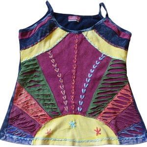 May include: A multi-coloured sleeveless top with a patchwork design. The top has a yellow, red, green, and blue colour scheme with a dark blue trim. The top has a distressed look with ripped fabric and visible stitching.