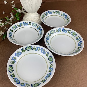 May include: Set of four white ceramic soup bowls with a blue and green floral pattern around the rim.