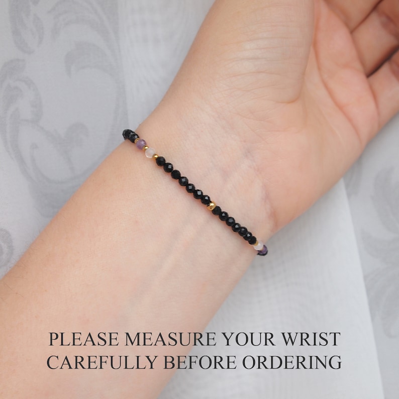 May include: A delicate bracelet with black onyx beads, gold spacers, and small purple and white beads. PLEASE MEASURE YOUR WRIST CAREFULLY BEFORE ORDERING.