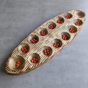Nordic Spruce Mancala Board: Rustic Charred Wood Game with Red Glass Pieces