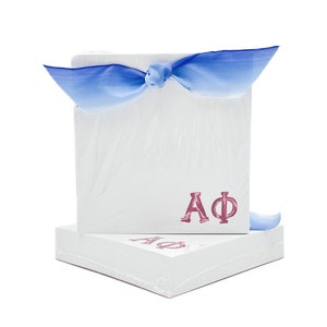 May include: A stack of white notepads with a blue ribbon tied around the top notepad. The top notepad has the letters "AΦ" printed in pink.