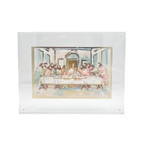 May include: A framed painting depicting the Last Supper, a biblical scene where Jesus shares a meal with his disciples. The painting is done in a watercolor style with muted colors and a gold frame.