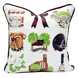 May include: Decorative throw pillow with a white background and a maroon border. The pillow features illustrations of a bulldog, a football helmet, a stadium, a church, a magnolia flower, and other collegiate-themed images.