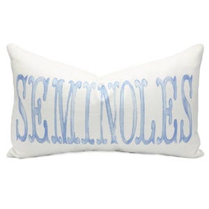 Puede incluir: Cojín rectangular blanco con la palabra "SEMINOLES" en letras de acuarela azul claro. El cojín tiene un aspecto texturizado y un aspecto suave y acogedor. Ideal para la decoración del hogar.