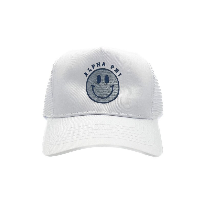 May include: White trucker hat with a blue smiley face and the text "ALPHA PHI" above it.